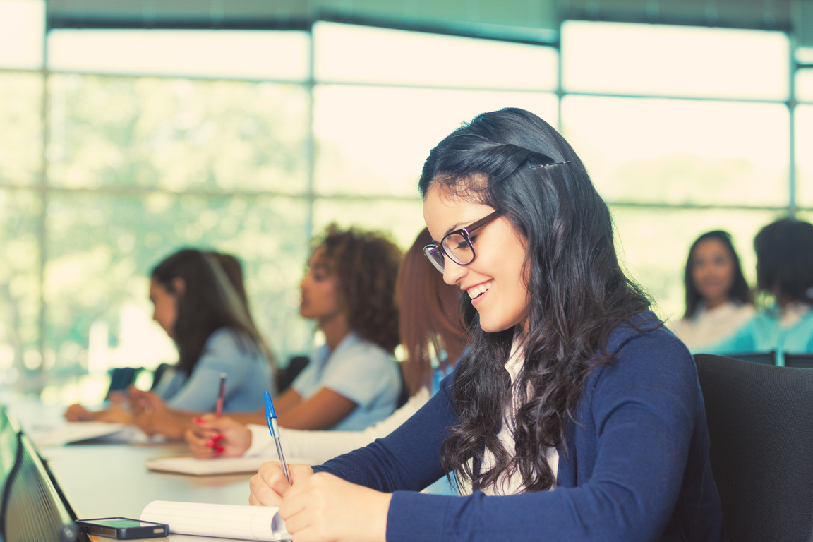 Happy student in private college prep school taking class notes